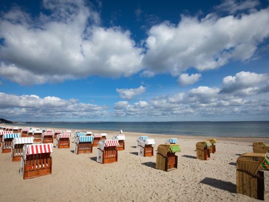 Geschlossene Strandkörbe stehen auf einem fast menschenleeren Strand an der Ostsee.
