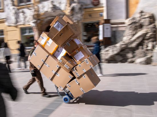 Ein Paketzulieferer transportiert mit einer Sackkarre mehrere Pakete durch die Münchener Innenstadt.