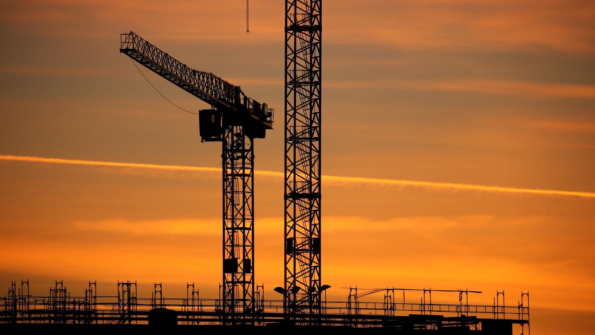 Baukräne einer Großbaustelle bei Sonnenaufgang. Die Stimmung in der Wirtschaft hat sich im Juli überraschend eingetrübt.
