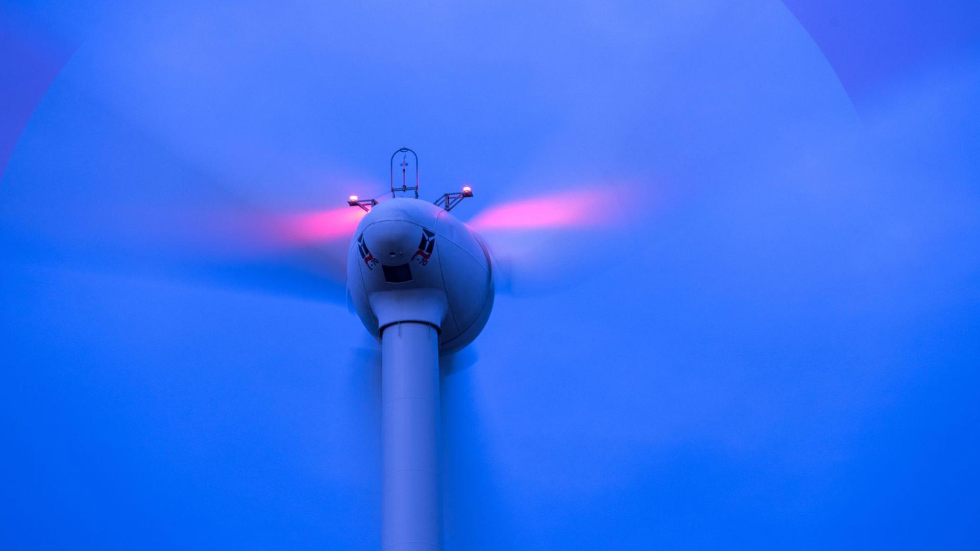 Windkraftanlagen drehen sich vor Sonnenaufgang in einem Windpark
