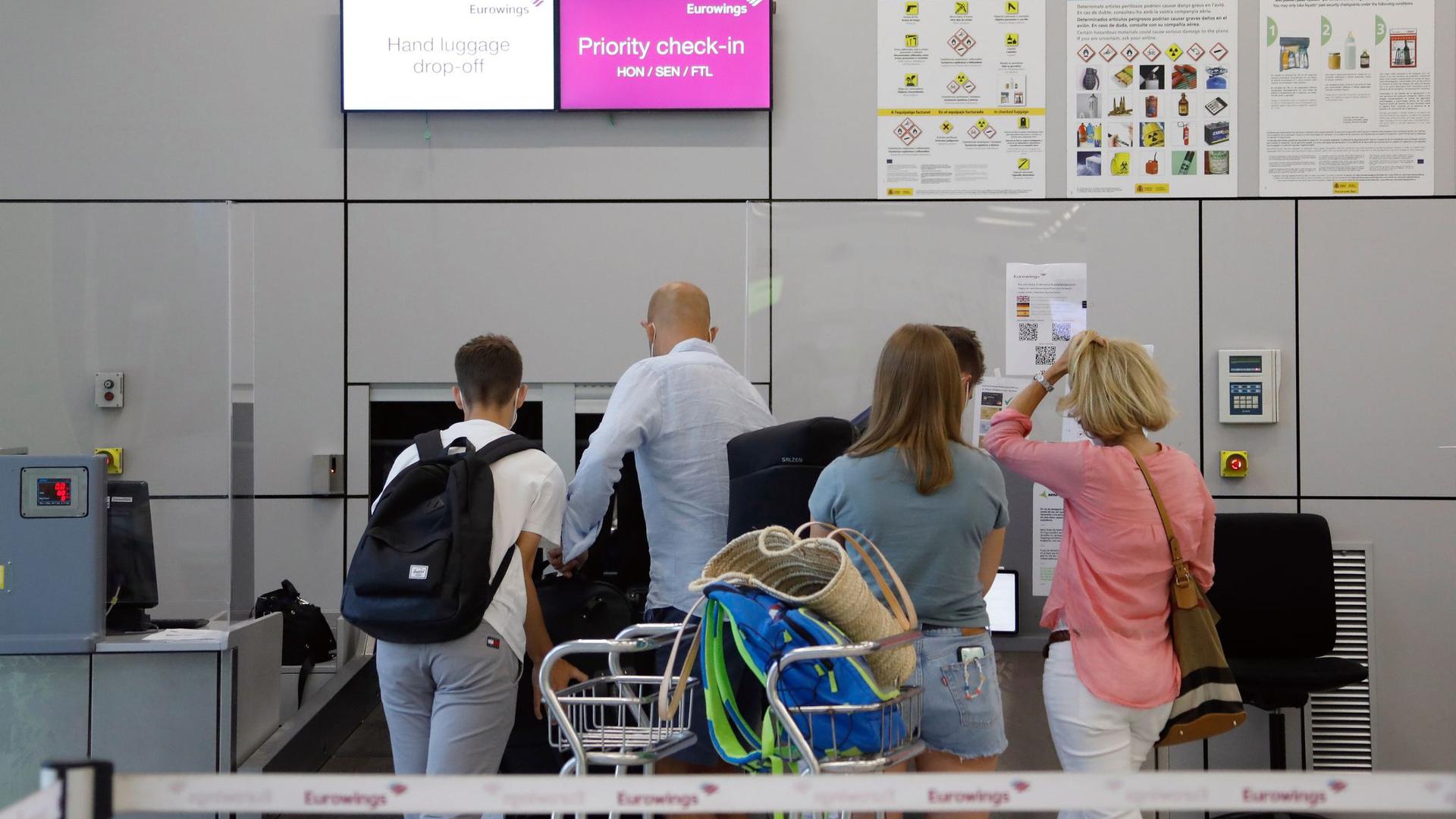 Fluggäste geben im Abflugbereich des Flughafens von Palma de Mallorca am Eurowings-Schalter ihre Koffer ab.