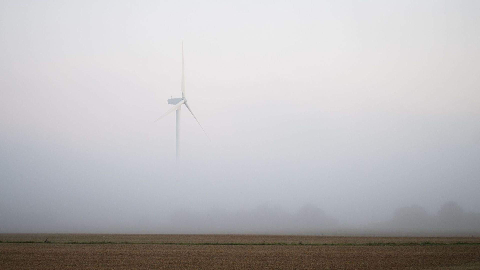 Ein Windrad ragt bei Hannover aus dem morgendlichen Nebel.