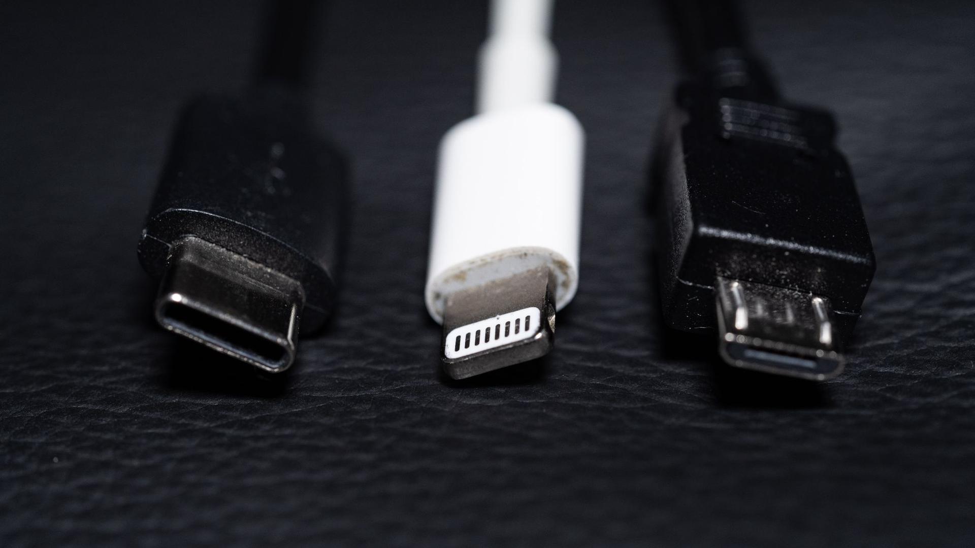 Ein USB-C (l-r), ein Apple Lightning und ein Micro-USB Kabel (l-r) liegen nebeneinander.