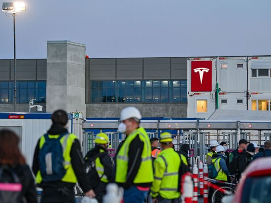 Arbeiter warten am frühen Morgen an einem Eingang zur Baustelle für die Tesla-Autofabrik.