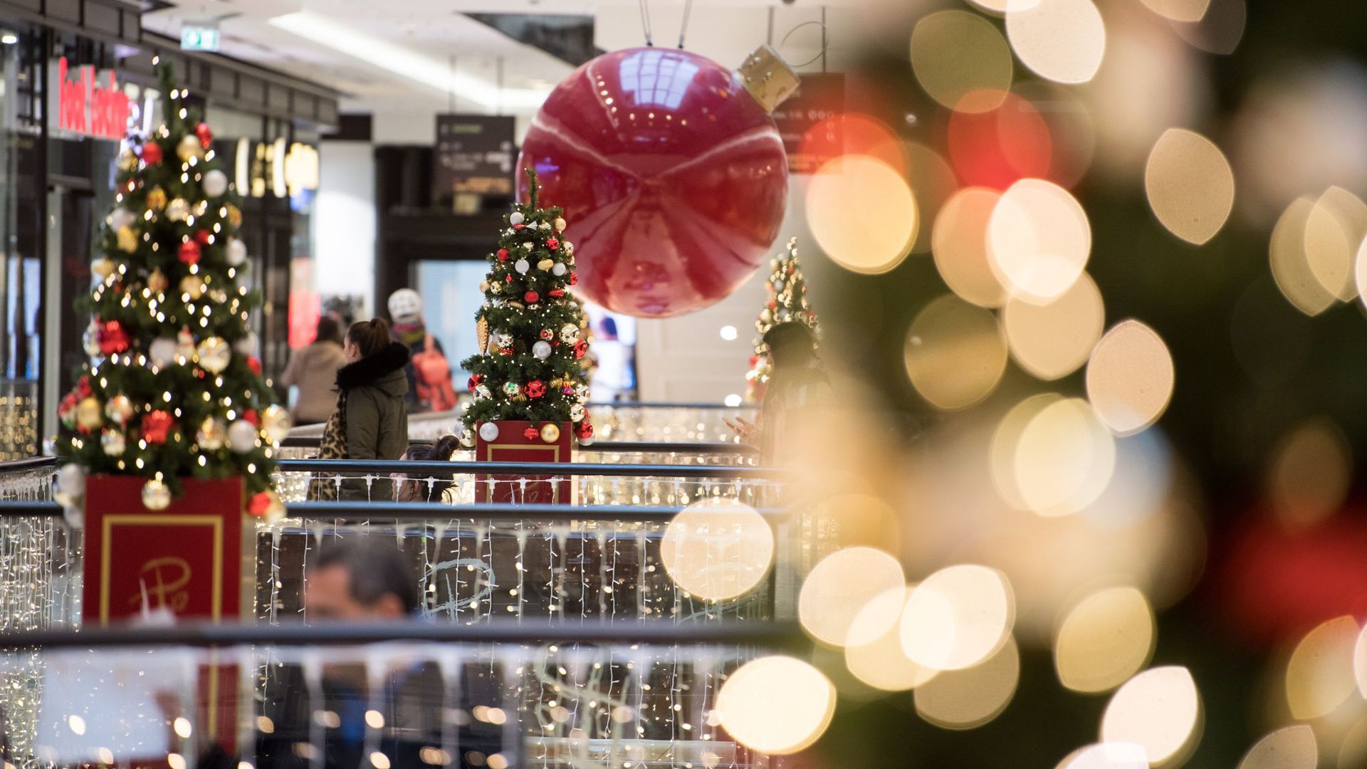 Kunden schlendern durch ein weihnachtlich geschmücktes Einkaufszentrum in Berlin.