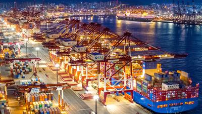 Containerschiffe liegen im nächtlich beleuchteten Containerterminal des Hafens von Qingdao.