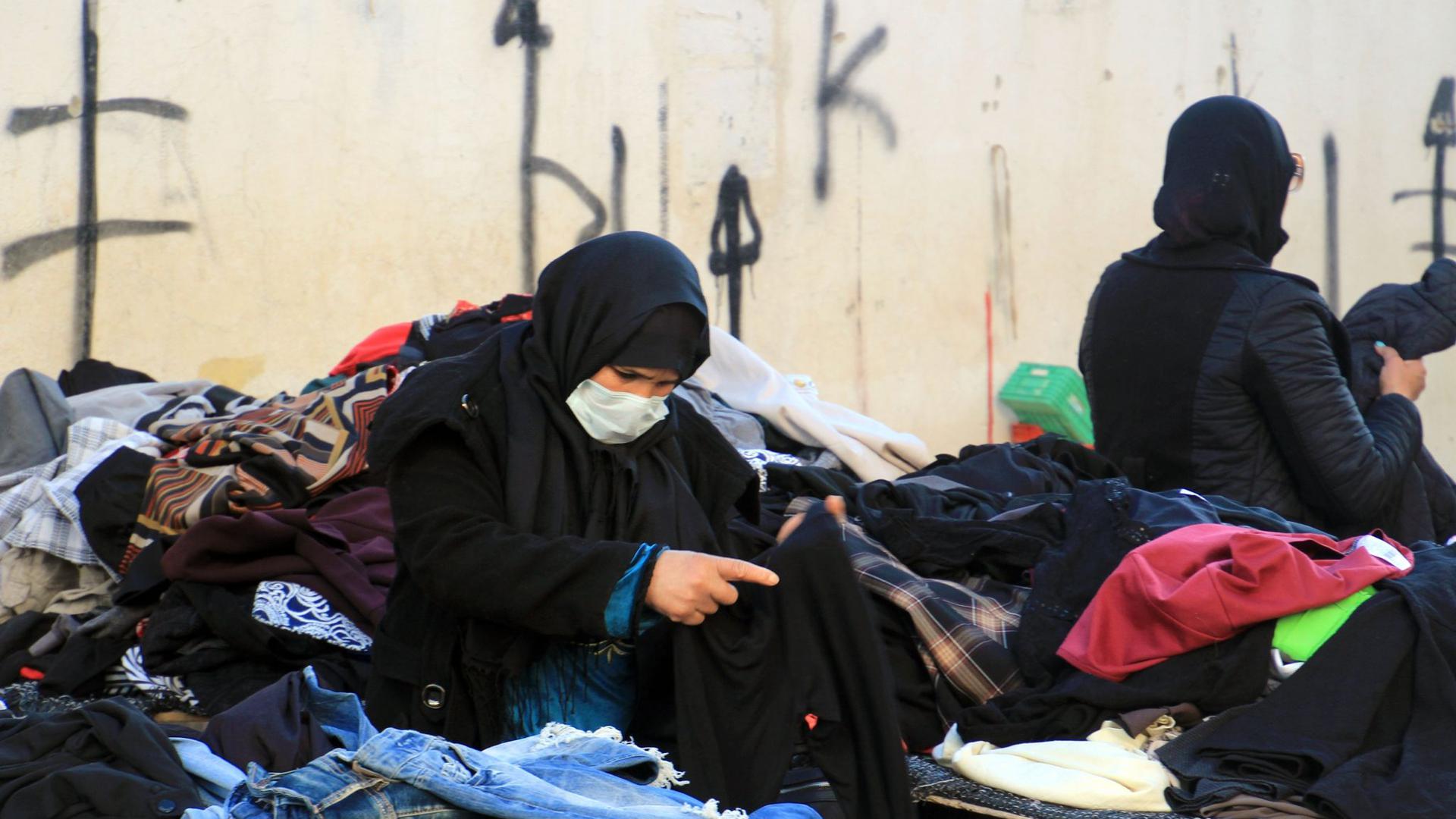 Eine Kundin schaut sich gebrauchte Kleidungsstücke auf einem zentralen Markt in Tunesiens Hauptstadt an.