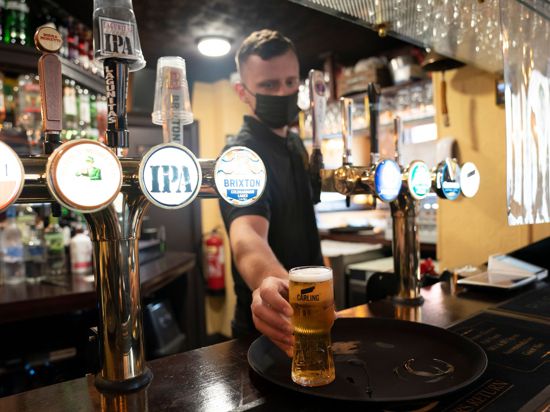 Ein Mitarbeiter eines Pubs serviert ein Bier. Trotz weitreichender Lockerungen von Corona-Regeln haben britische Pubs erneut deutlich weniger Bier verkauft als vor der Pandemie.