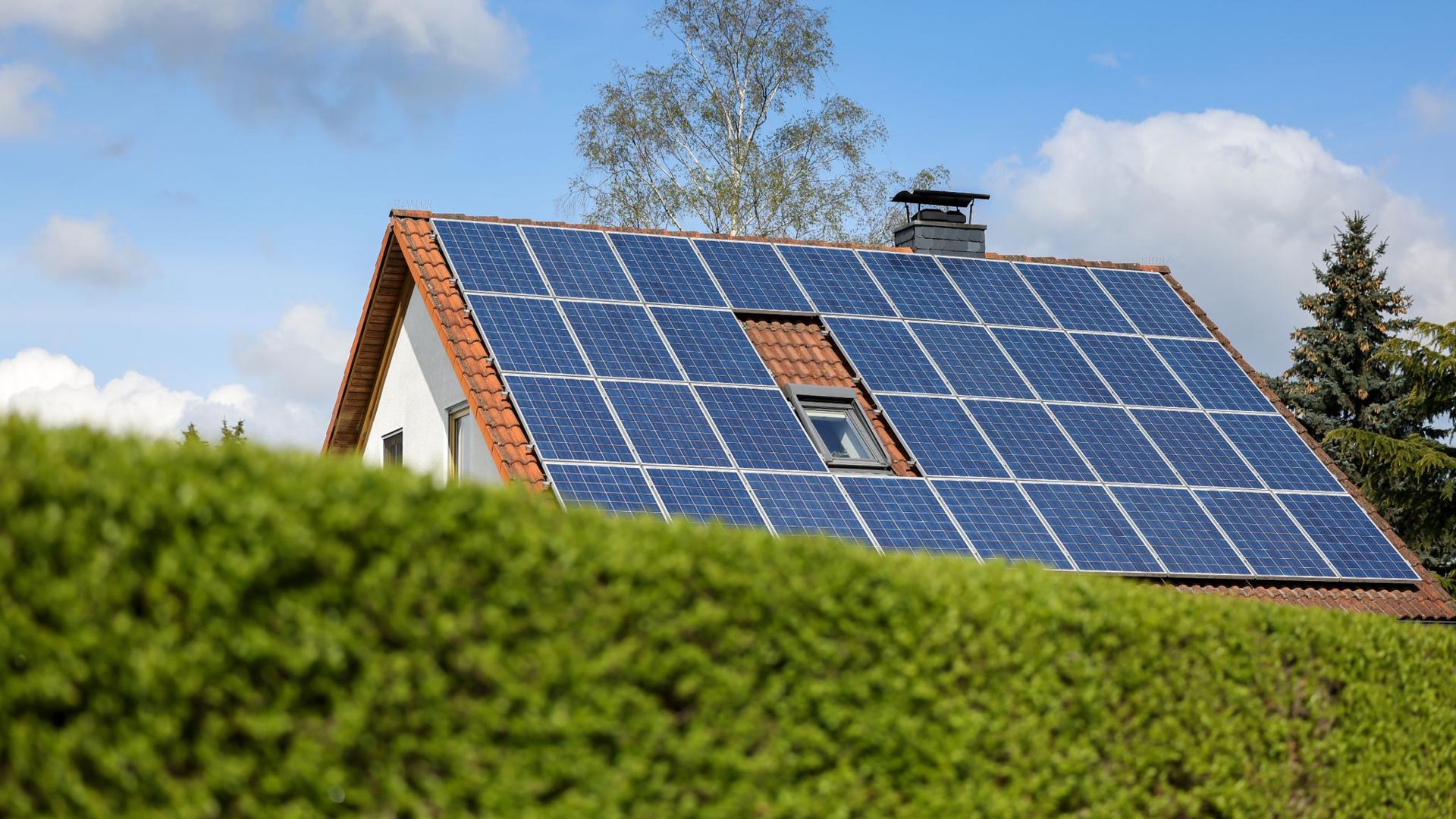 Ein Einfamilienhaus mit Solarpaneelen auf dem Hausdach.