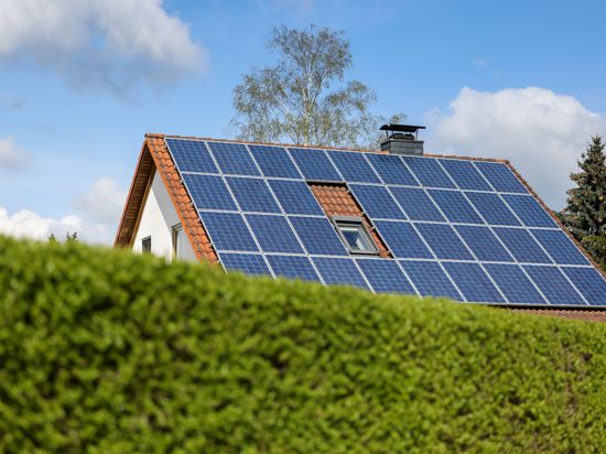 Ein Einfamilienhaus mit Solarpaneelen auf dem Hausdach.