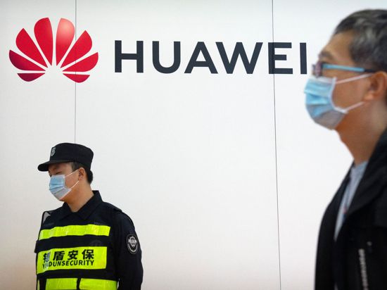 Ein Wachmann steht auf der PT Expo in Peking an einem Stand des chinesischen Technologieunternehmens Huawei.