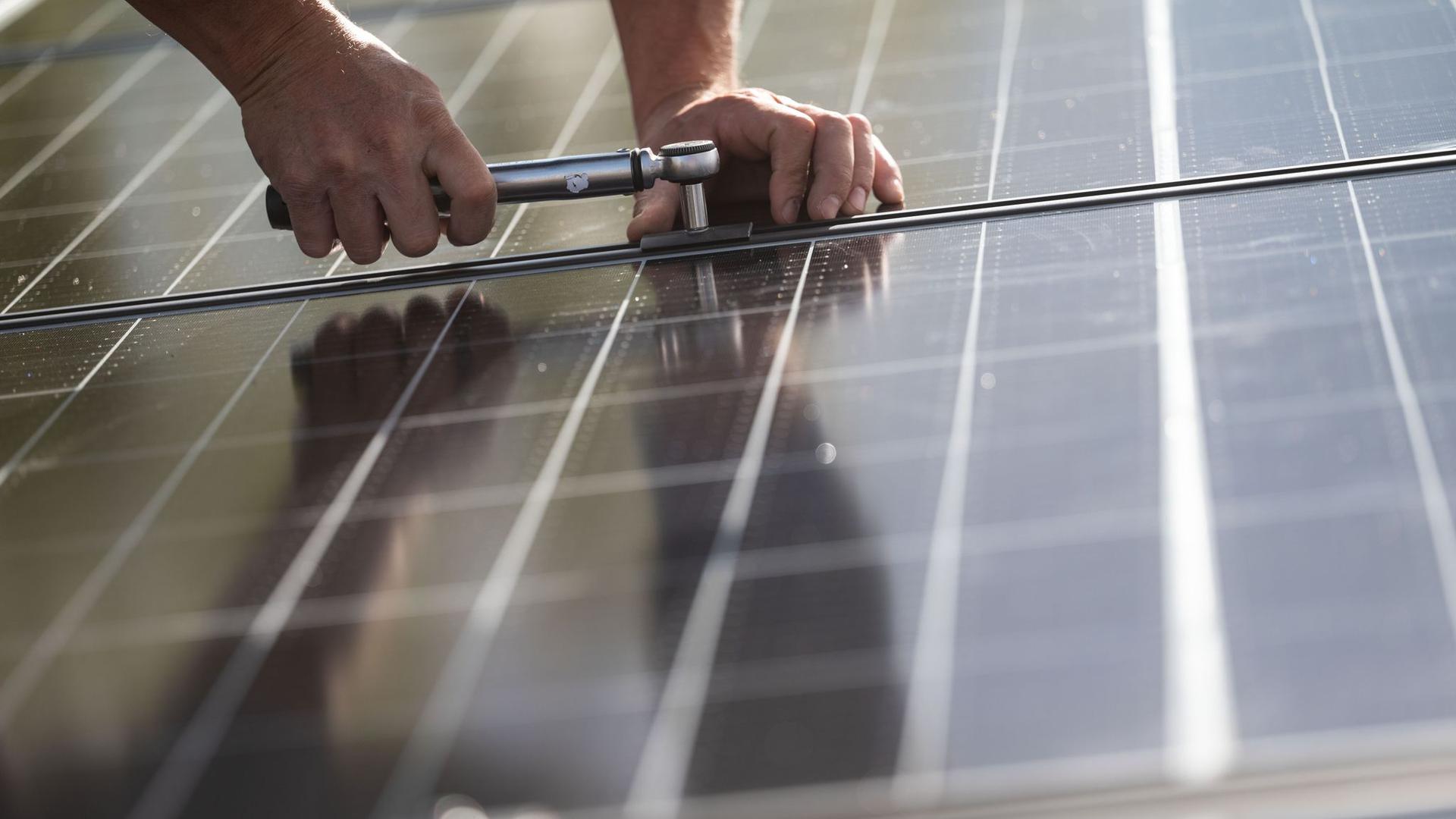 Ein Arbeiter montiert Photovoltaikmodule auf dem Dach eines Wohnhauses. Das Comeback der Solarbranche in Deutschland lockt Investoren an.
