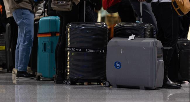 Passagiere mit Koffern warten am Check-In Schalter am Frankfurter Flughafen.