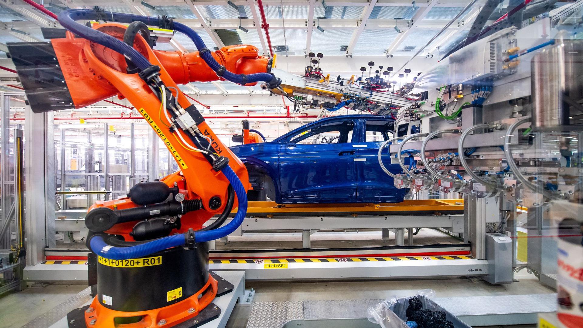 Roboter montieren Bauteile eines E-Autos. Der Halbleitermangel dürfte die Autoindustrie einer Studie zufolge bis mindestens 2024 bremsen.