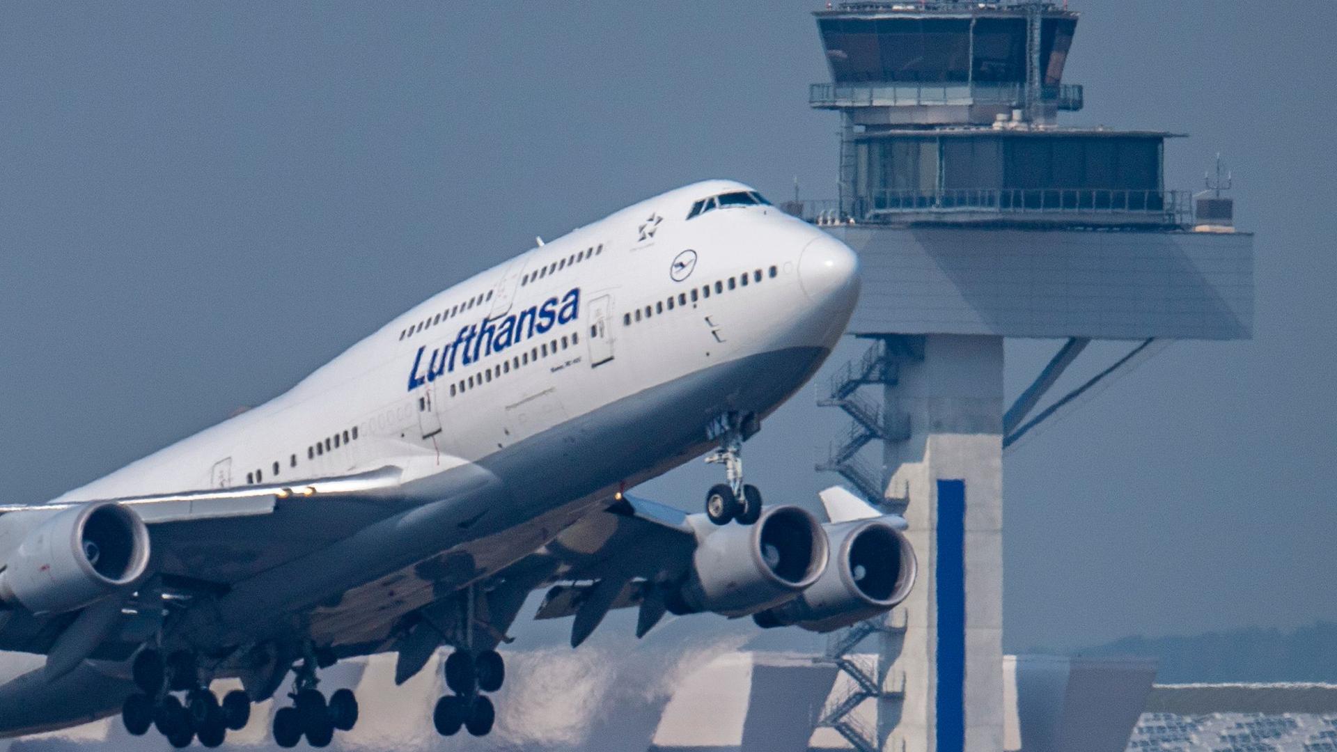 Eine Passagiermaschine vom Typ Boeing 747 der Lufthansa startet vor dem Tower des Flughafens Frankfurt zu einem Transatlantikflug.