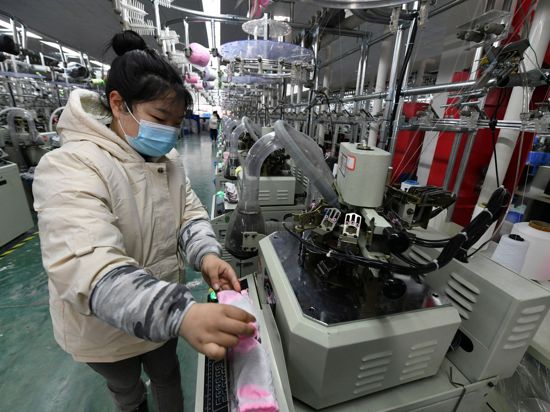 Eine Arbeiterin bedient eine Maschine zum Stricken von Socken in einer Fabrik im Kreis Funan in der zentralchinesischen Provinz Anhui.