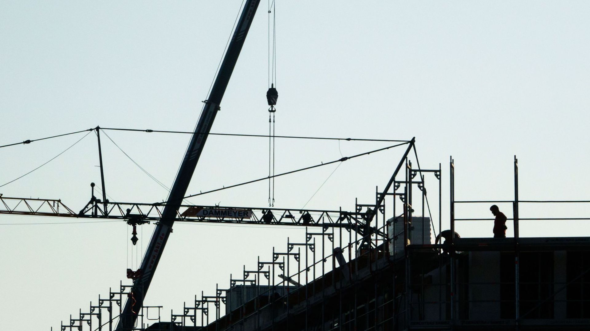 Bauarbeiter stehen in einem Neubaugebiet beim Bau eines Mehrfamilienhauses.