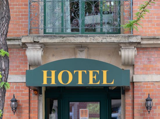 Ein Schild mit der Aufschrift „Hotel“ hängt an einem Hauseingang.