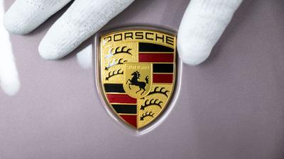 Ein Mitarbeiter der Porsche AG zeigt das Porsche-Logo.