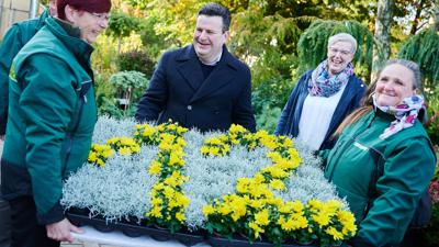Bundesarbeitsminister Hubertus Heil (m.) mit Blumengesteck zum Mindestlohn beim Besuch einer Gärtnerei in Berlin.
