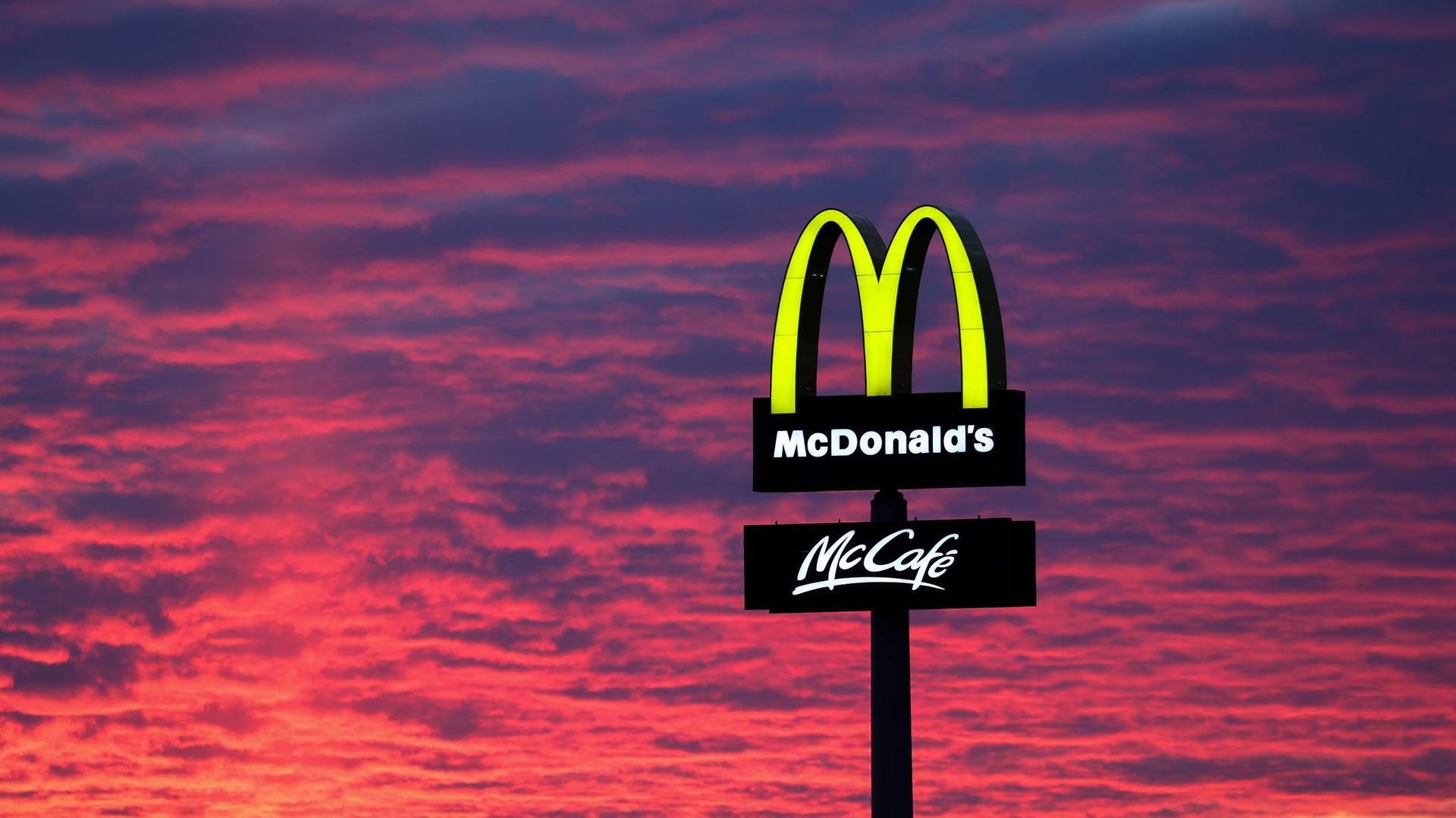 Der Abendhimmel leuchtet hinter McDonald's. Die Fastfood-Kette bleibt größter Arbeitgeber unter den US-Firmen in Deutschland.