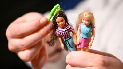 Eine junge Frau kämmt die Haare von zwei der größeren Polly Pocket Puppen.