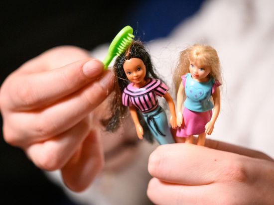 Eine junge Frau kämmt die Haare von zwei der größeren Polly Pocket Puppen.