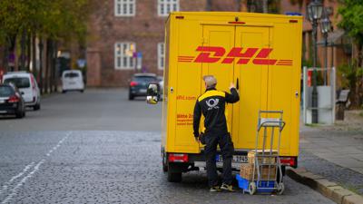 Ein Zusteller entlädt ein Fahrzeug von DHL in Lüneburg.