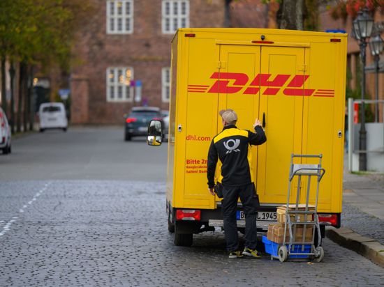 Ein Zusteller entlädt ein Fahrzeug von DHL in Lüneburg.