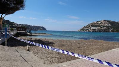 Mit einem Absperrband der Polizei ist der Zugang zu einer Badestelle auf Mallorca im Frühjahr 2020 wegen der Corona-Pandemie abgesperrt.