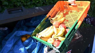 Ein Mitarbeiter eines Supermarktes bringt Obst zu einem Müllcontainer.