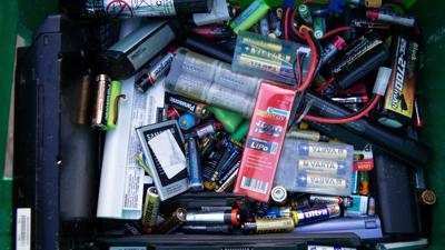 Alte Batterien und Akkus in einem Sammelbehälter auf einem Recyclinghof.