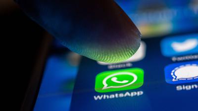 Ein Finger berührt das WhatsApp-Logo auf einem Smartphone.