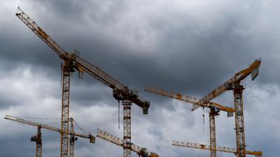 Dunkle Wolken ziehen über die Kräne auf einer Baustelle. „Alle Indikatoren am Bau zeigen deutlich nach unten, eine Trendwende ist nicht in Sicht“, stellt die Bauindustrie fest.