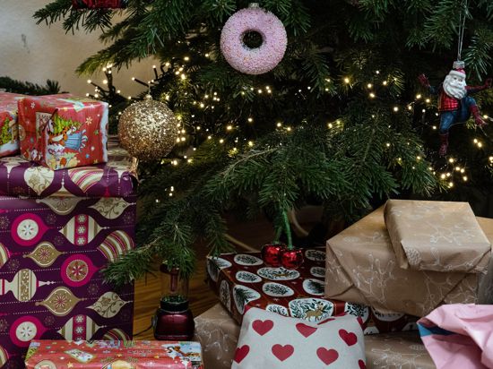 Eingepackte Geschenke liegen unter einem geschmückten Weihnachtsbaum. Die Menschen in Deutschland wollen in diesem Jahr bei den Präsenten sparsamer sein.