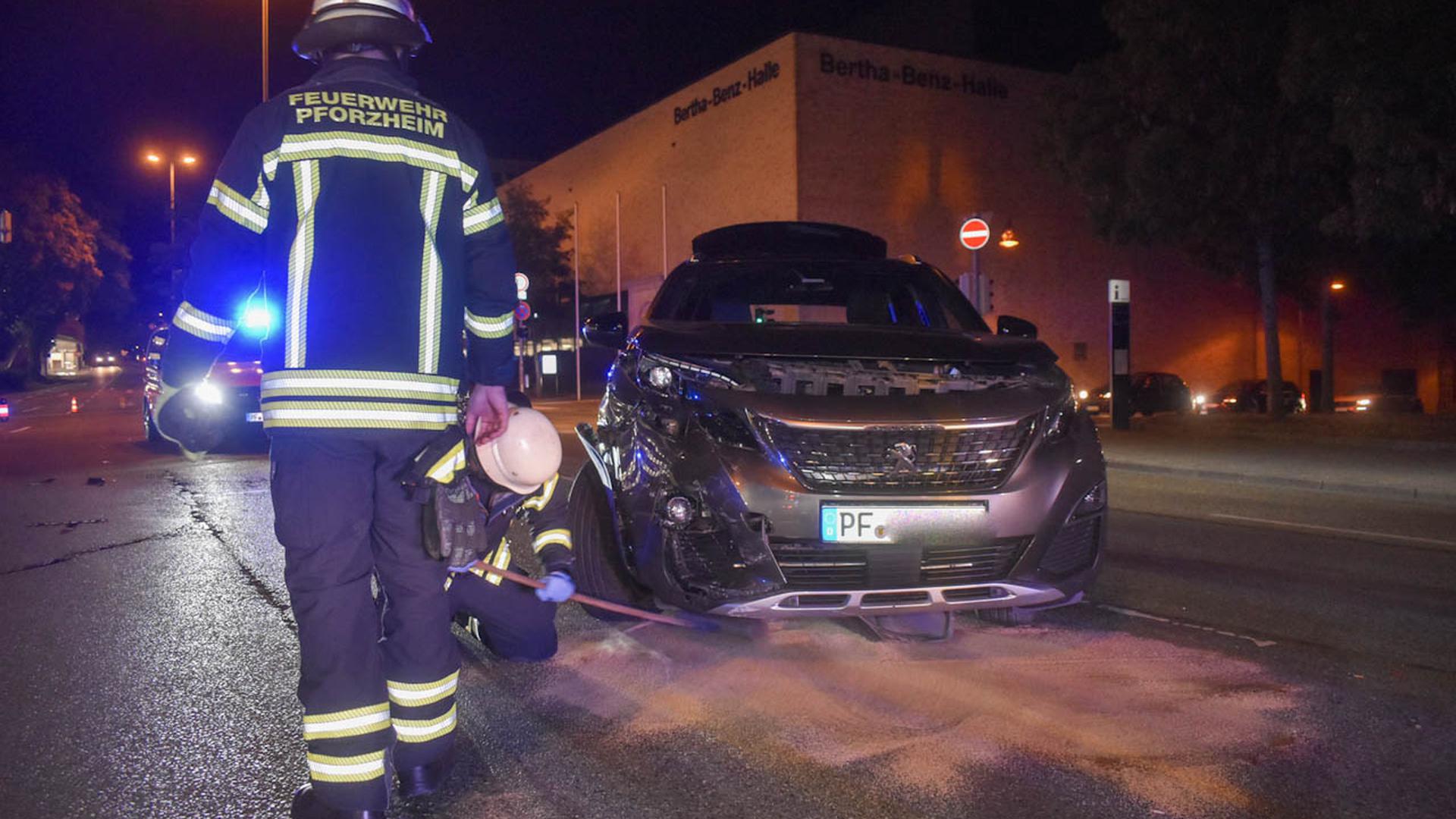 Ein Feuerwehrmann streut Bindemittel unter ein verunfalltes Auto, das Betriebsflüssigkeiten verliert.