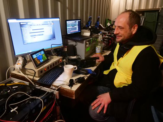 Ein Mann sitzt in gelber Warnweste vor einem Computer.