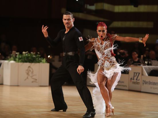 Marius-Andrei Balan in schwarzem Dress und gerader Körperhaltung tanzt neben Khrystyna Moshenska mit roten Haaren und einem wilden weißen Kleid im CCP.