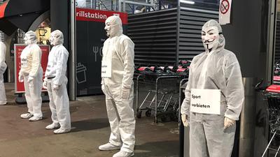 Bei einer Protestaktion in Pforzheim auf der Wilferdinger Höhe stehen einige Menschen ganz in weiß gekleidet mit Masken vor der Kaufland-Filiale.