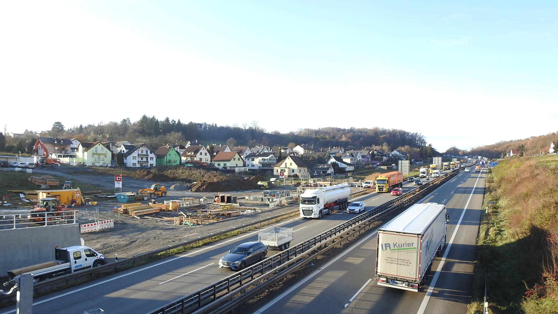 Autos und Lastwagen fahren auf der A8 im Enztal bei Pforzheim, daneben ist die Baustelle zu sehen.