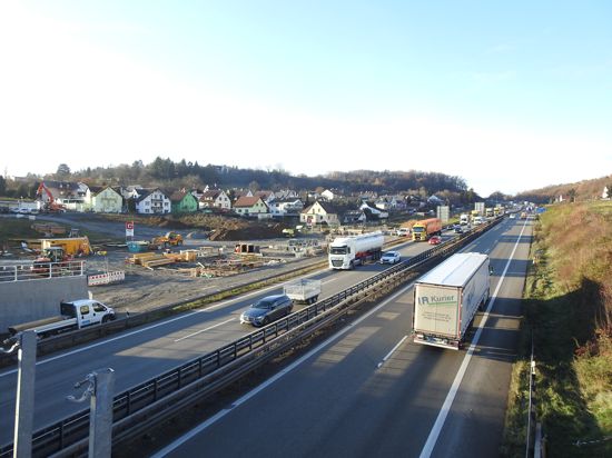 Autos und Lastwagen fahren auf der A8 im Enztal bei Pforzheim, daneben ist die Baustelle zu sehen.