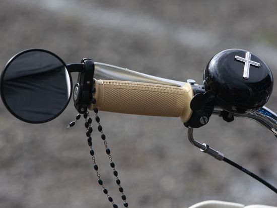 Eine Fahrradklingel mit einem Kreuz ist am Lenkrad eines Mopeds beim Biker-Gottesdienst befestigt. Zum EKM-Bikergottesdienst unter dem Motto «Spur halten» ist zum Saisonende in die Motorsport Arena Oschersleben eingeladen worden. +++ dpa-Bildfunk +++