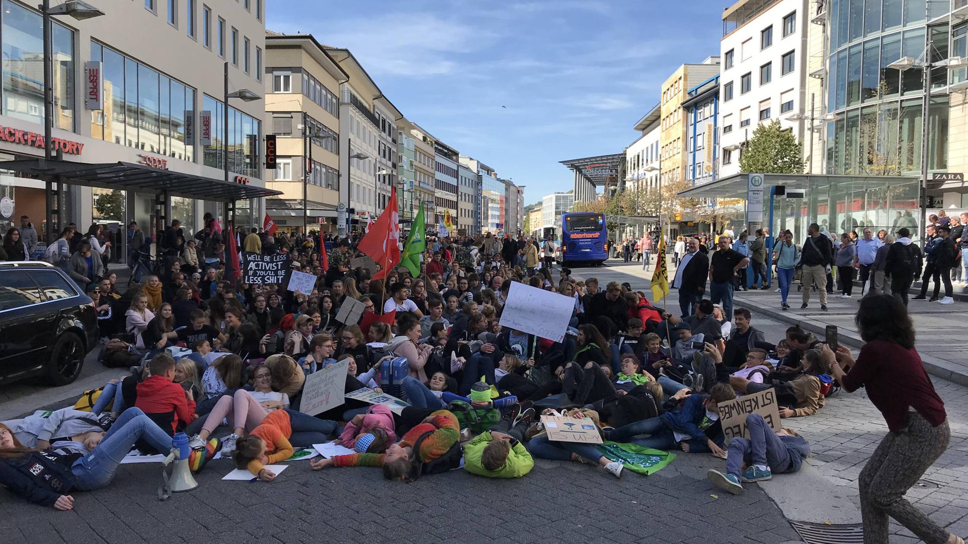 Junge Demonstranten sitzen in einem größeren Pulk auf der Straße