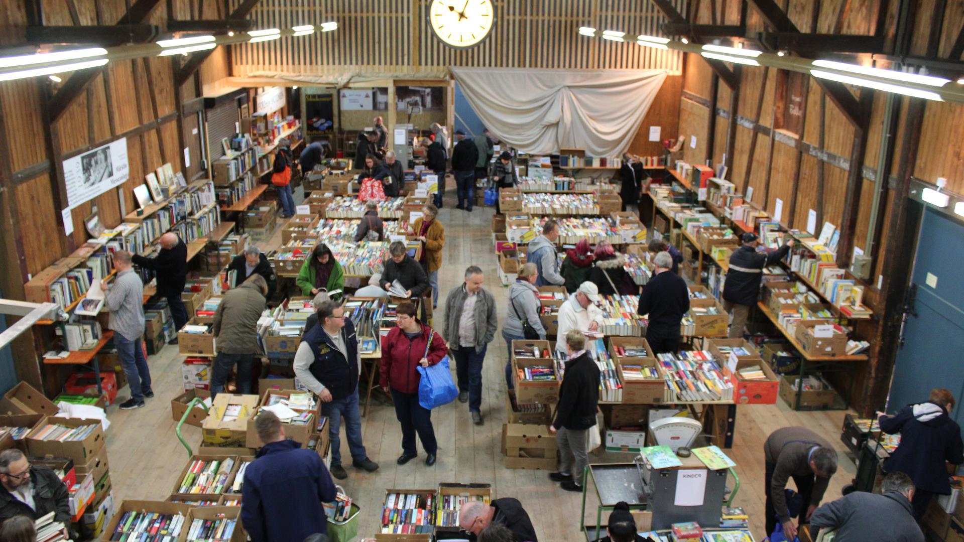 Viele Besucher gruschteln in der Güterhalle des Weißensteiner Bahnhofs in Kartons mit Büchern.