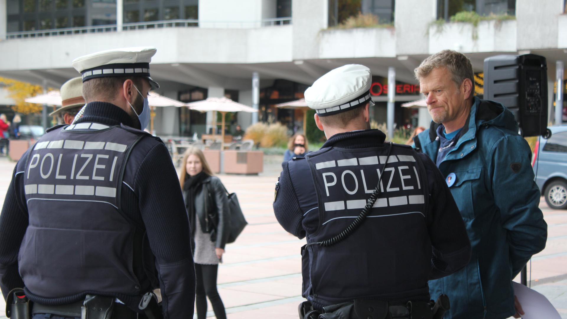 Zwei Polizisten weisen bei der Demonstration der Gegner der Corona-Auflagen vor dem Pforzheimer Rathaus auf die Maskenpflicht hin. Die meisten Teilnehmer trugen keinen Mundnasenschutz.