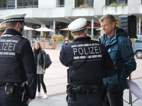 Zwei Polizisten weisen bei der Demonstration der Gegner der Corona-Auflagen vor dem Pforzheimer Rathaus auf die Maskenpflicht hin. Die meisten Teilnehmer trugen keinen Mundnasenschutz.