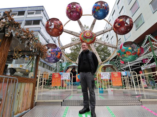 Schausteller Stefan Doss aus Waiblingen steht vor einem bunten Kinder-Riesenrad auf dem Pforzheimer Marktplatz 