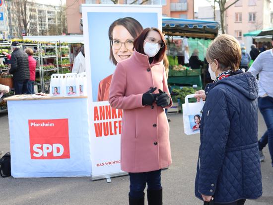 Zwei FRauen im Gespräch, im Hintergrund ist ein Infostand der SPD-Kandidatin aufgebaut, zudem sind verschiedene Marktstände im Bild.
