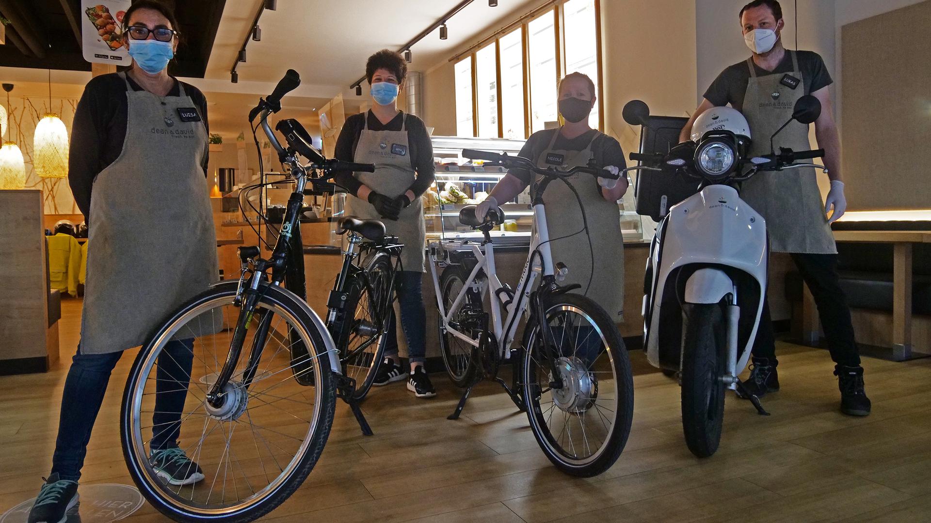 Vier Personen stehen mit Fahrrädern und Elektroroller in einem Gebäude.