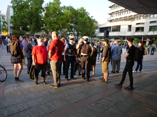 Kundgebung zur Lage der Flüchtlinge in Lesbos vor dem Rathaus Pforzheim mit Polizei und zwei Mitglieder von „Ein Herz für Deutschland“ in roten T-Shirts, die in Richtung Platz von Kundgebungsteilnehmern abgeschirmt werden. Ralf Fuhrmann blaues Hemd von links